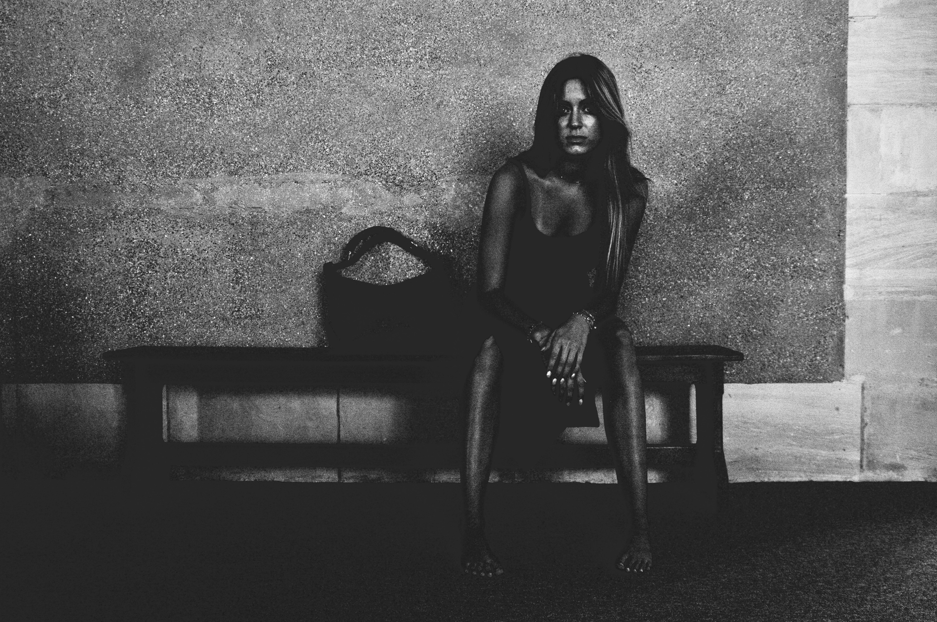 Seated on a bench against a concrete wall