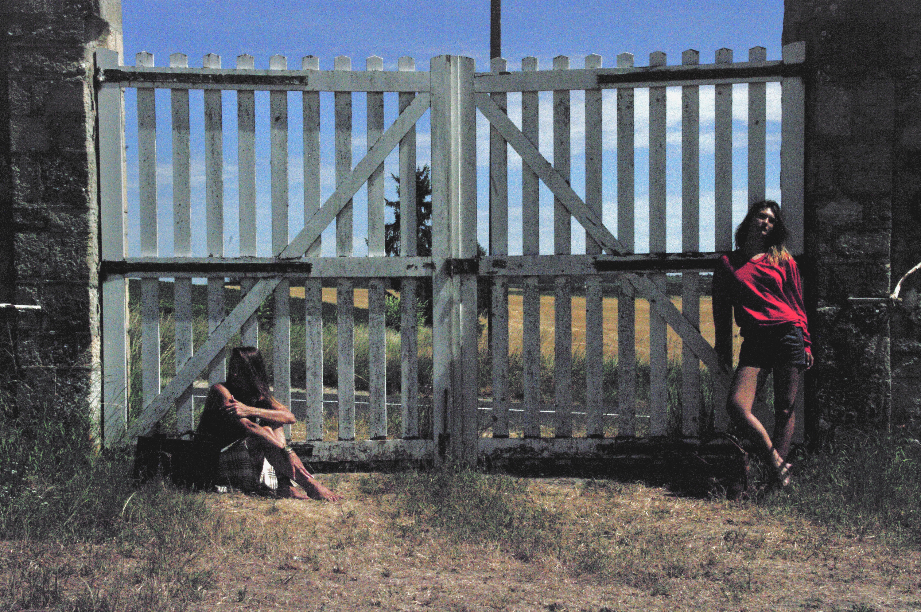Two figures at the wooden gate, one seated, one standing