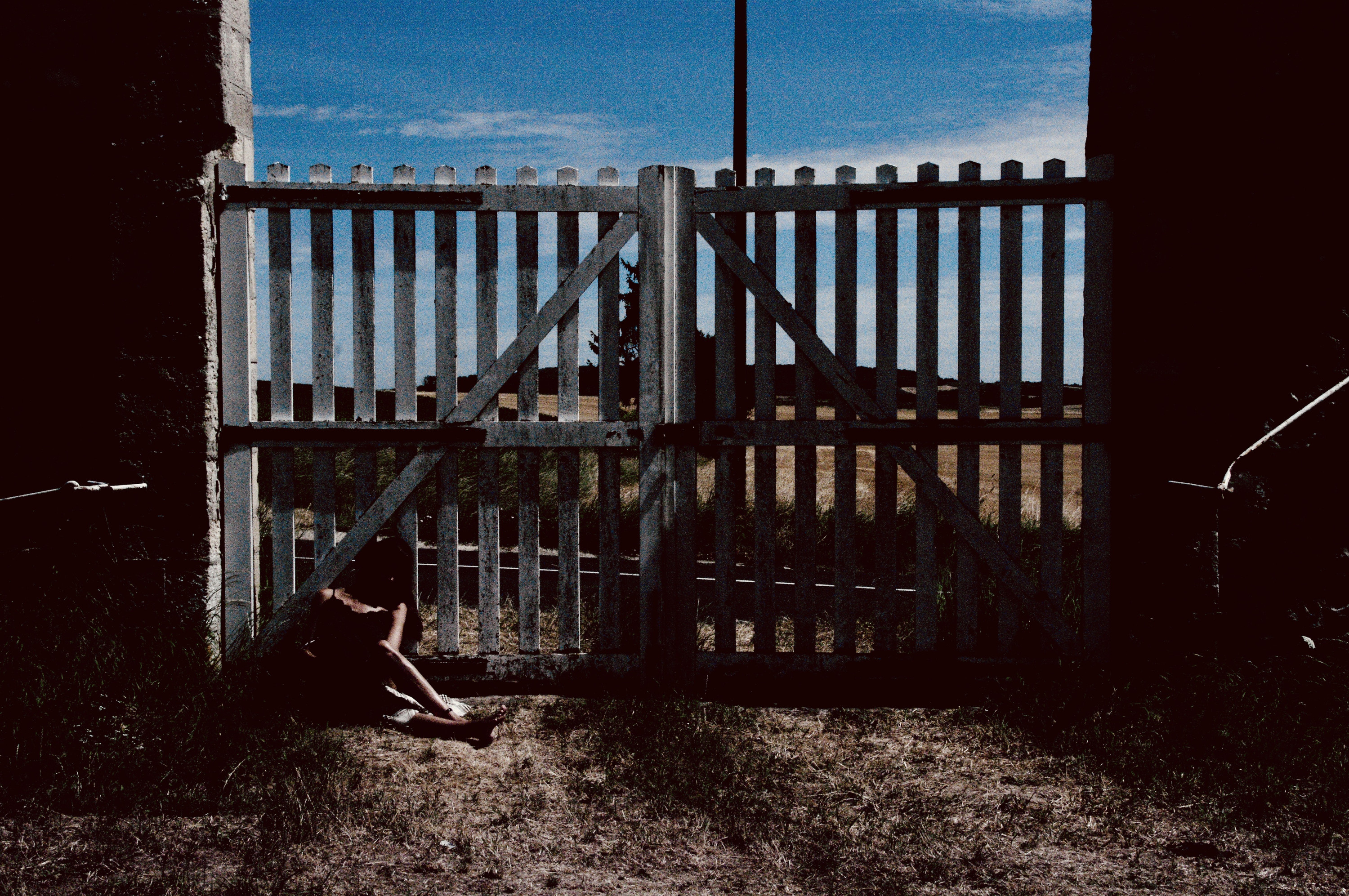 Seated against the wooden gate, dusk