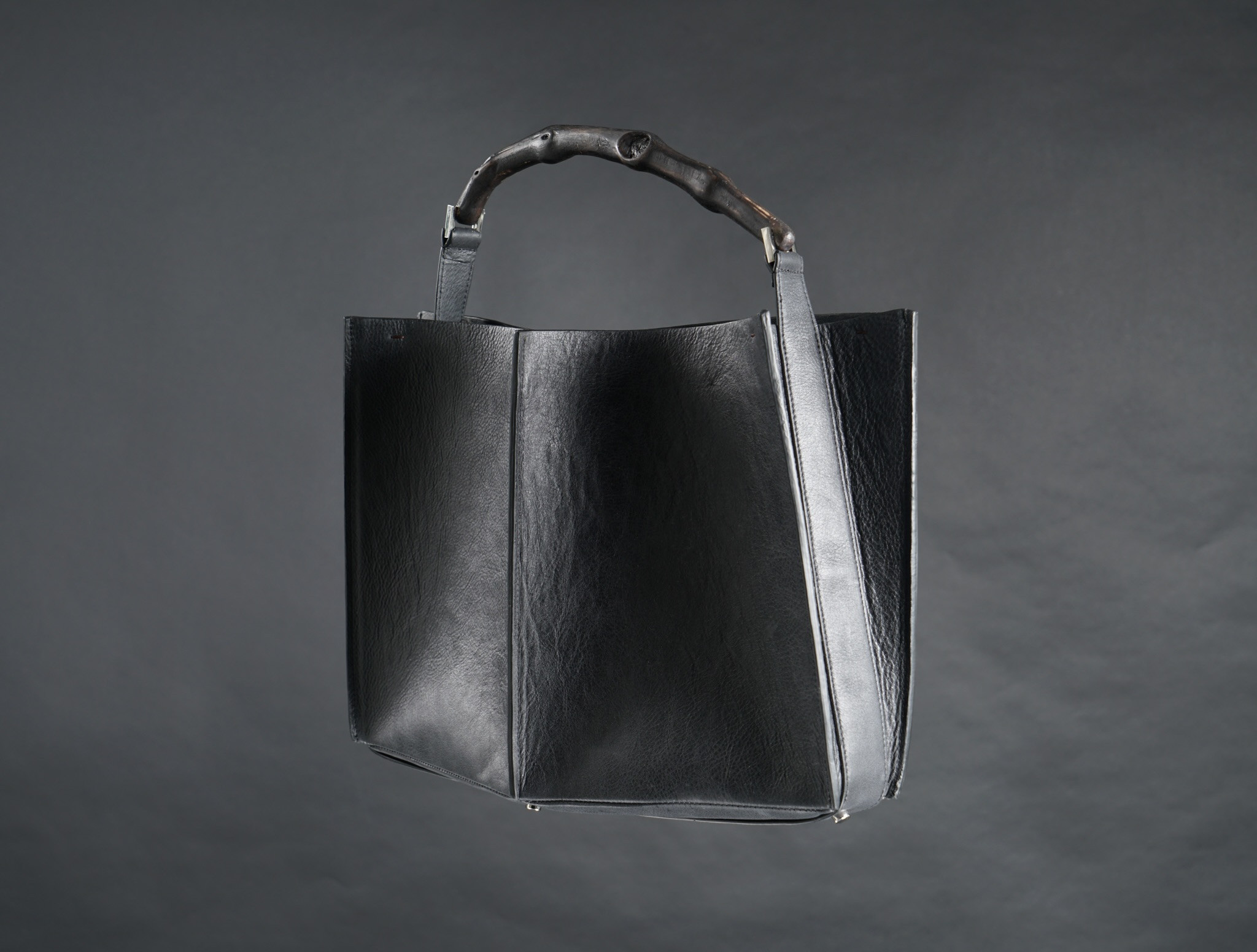 HÉRITAGE — structured black calfskin bag with vine-wood handle, front view
